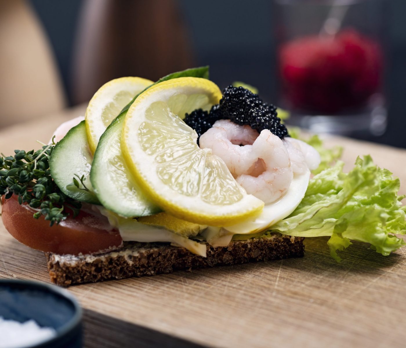 Smørrebrød is a traditional open faced sandwich made with dark rye bread with various cold toppings. Toppings range from egg, smoked fish to cold meats with various pickles and herbs added. Traditionally eaten at lunchtime or occasionally at the end of a party. Egg with prawn and caviar, colour, horizontal with some copy space.