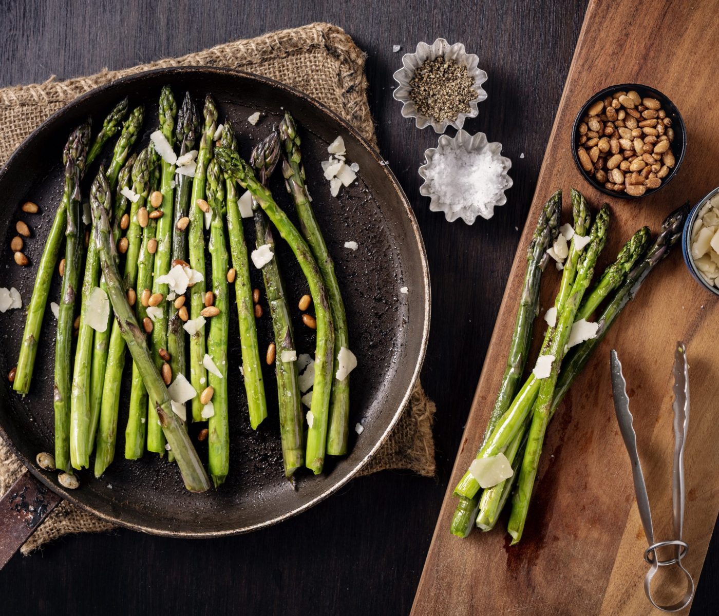 Pan fried asparagus served from the skillet. Cooked with a tiny bit of oil or butter just give a bit of colour and taste to the asparagus stems. Served with; pine nuts, vegan parmesan cheese and salt and pepper.Overhead view, horizontal format with some copy space.